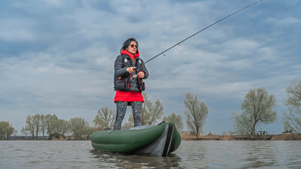 A lady standing in a kayak while fishing.